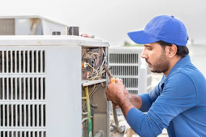 Technician inspecting the electrical compartment of an outdoor air conditioning unit