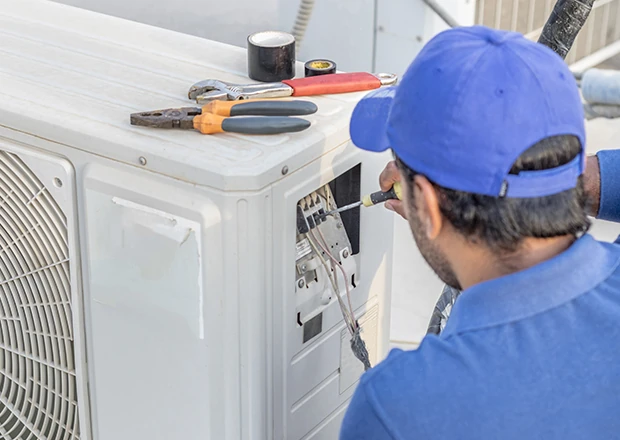 Technician checking an outdoor condenser with service tools nearby